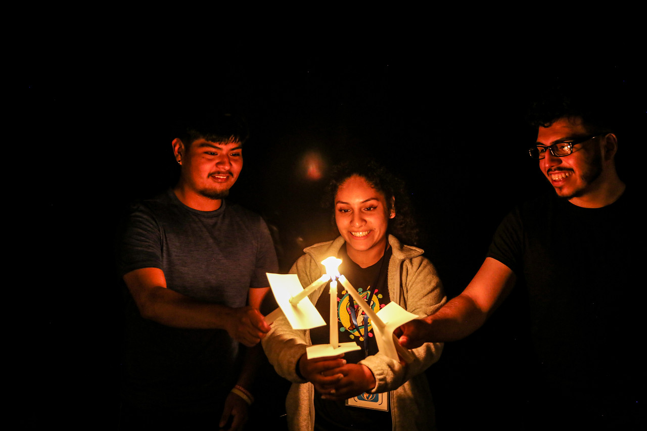 three people lighting each others candles