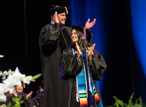 John and Zoe Kiraly on Stage Together During the 2024 College of Law Commencement Ceremony