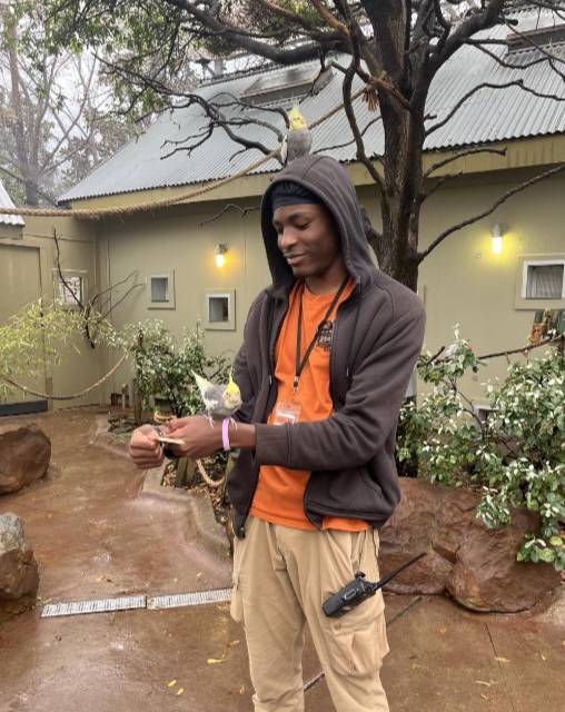 Dalon Moore Holds One Bird While Another Perches Itself on His Head at the Dallas Zoo