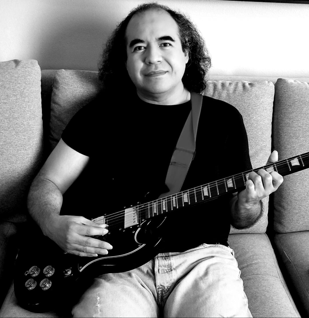 black and white photo of mike sitting and holding a guitar